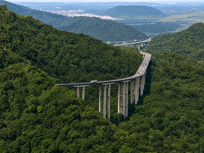 Rodovia sinuosa entre morros arborizados no caminho para a região